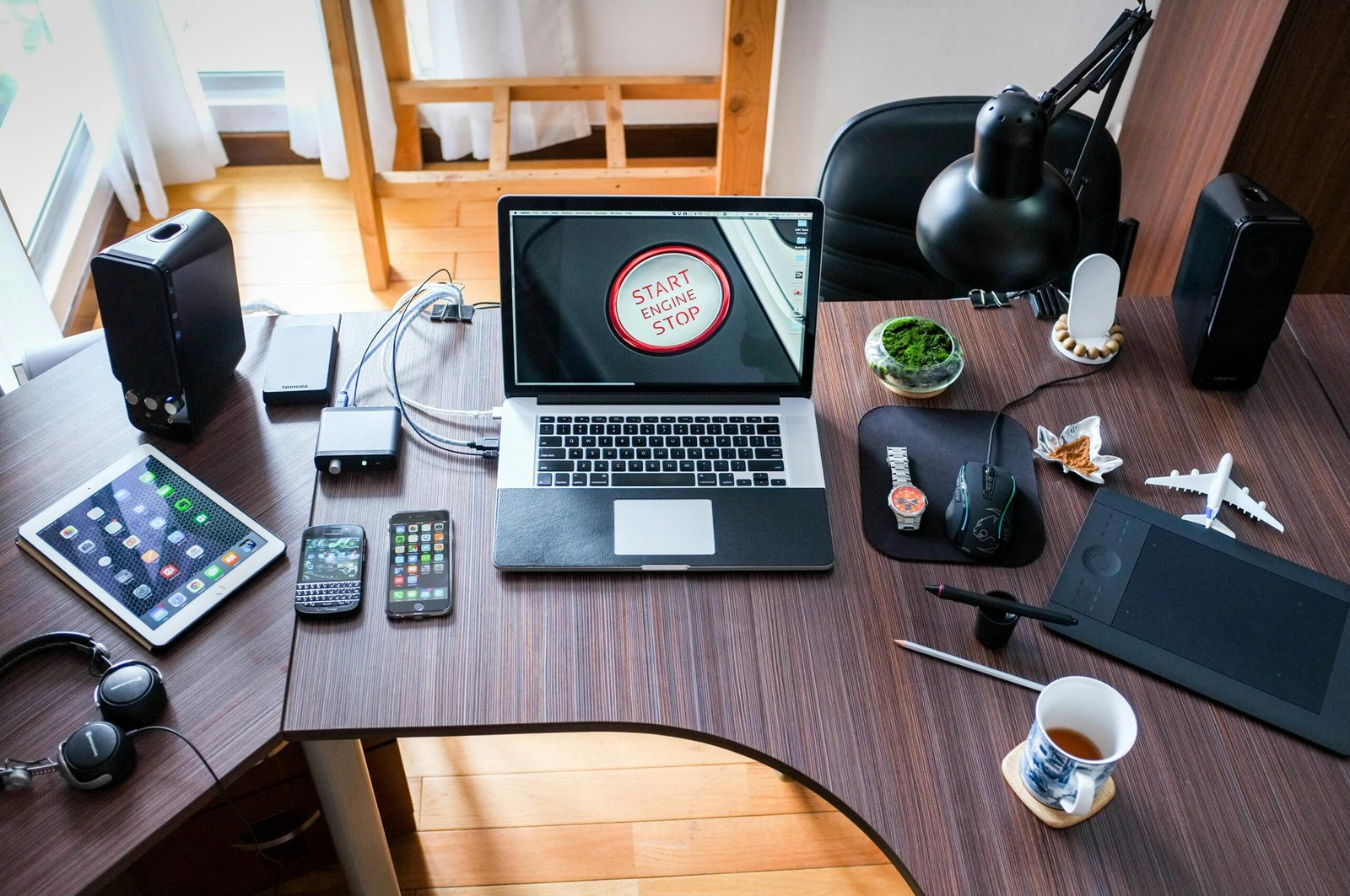 A laptop, tablet, and a cup of tea set on a table, symbolizing a space where tech innovations come to life and ideas are brewed.